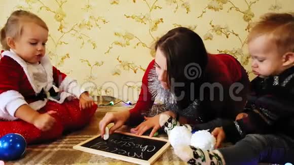 妈妈和女儿在黑板上画新年的属性妈妈和女儿正在画一棵圣诞树新年视频的预览图