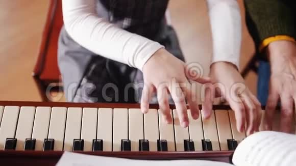 音乐课女孩弹钢琴年长的老师坐在她身边帮助演奏从顶部看视频的预览图