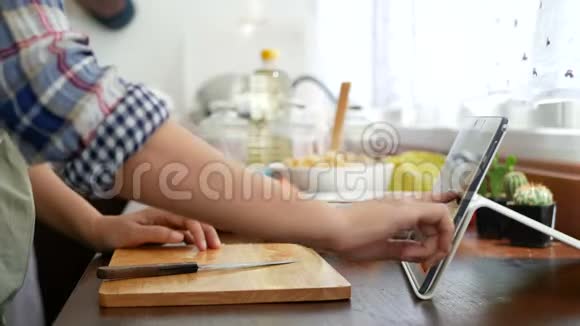 4K女人用手指滑在平板电脑上切红番茄准备烹饪原料烹饪在线视频剪辑视频的预览图