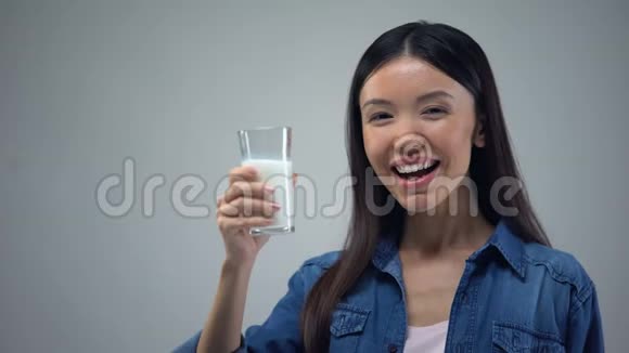 开朗的女人把一杯牛奶照进相机有益健康的细菌视频的预览图