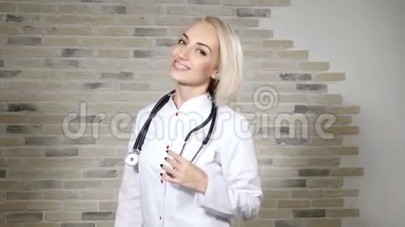 一位年轻漂亮的女医生的肖像脖子上戴着一个电话显示器看着镜头微笑卫生保健意识4公里视频的预览图