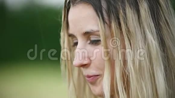 在户外的一场雨中一位美丽迷人的白人金发女孩头发湿漉漉的在大自然中的一幅特写照片视频的预览图