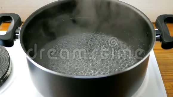 厨房电炉上的平底锅里的水会随着气泡沸腾视频的预览图