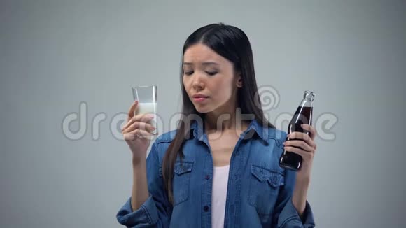 女人试图在不健康的碳酸饮料和有用的健康牛奶之间做出选择视频的预览图
