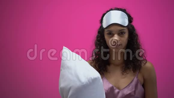 穿着睡衣戴着眼罩抱着枕头打哈欠的的非裔美国妇女视频的预览图