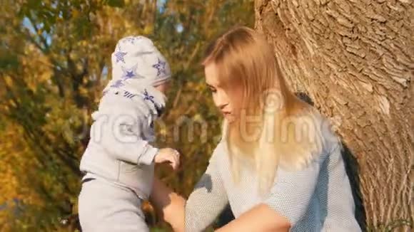 年轻的母亲坐在草地上花时间和她的小婴儿在一起视频的预览图
