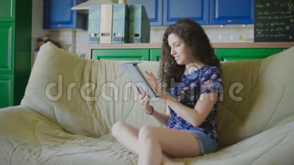 美女坐在沙发上用现代平板电脑购物视频的预览图