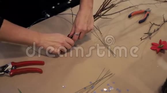 女性双手用蓝色金属丝连接木棒制作花环视频的预览图