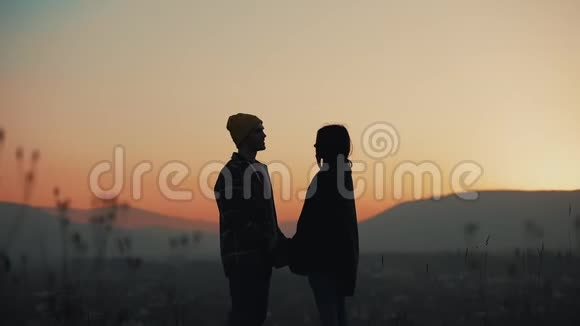 这对夫妇的剪影是在日落时分双手捧着五彩缤纷的天空视频的预览图