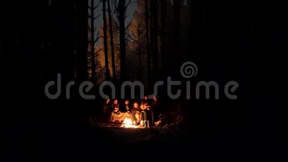 冬天森林里的年轻人坐在火堆旁加入助燃剂篝火爆炸视频的预览图