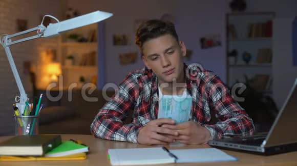 十几岁的男孩数着欧元钞票想着新的购买做梦视频的预览图