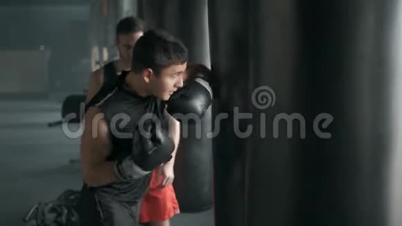 拳击手和他的教练在体育馆的拳击袋上练习一些动作4K慢动作视频的预览图