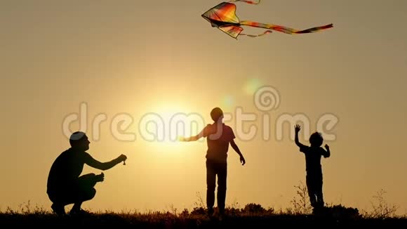 快乐的父亲把蛇带到空中两个孩子在玩嬉戏跳过风筝家庭团结视频的预览图
