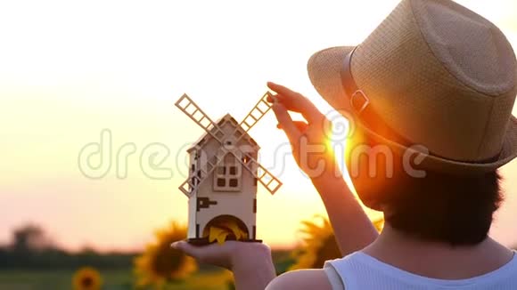 女孩站在向日葵的田野里手里拿着一个玩具风车磨坊的手在转动视频的预览图