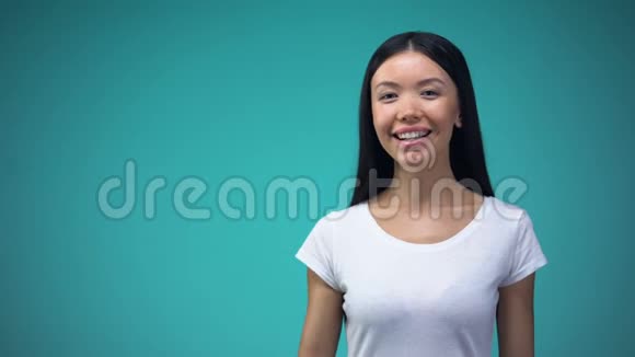 活泼开朗的亚洲女性显示ok标志在蓝色背景上隔离模板视频的预览图