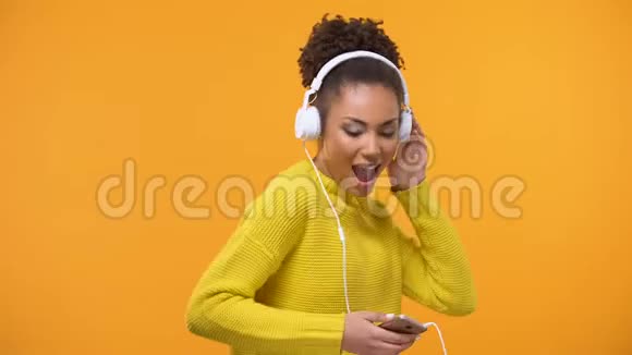 一位身穿耳机在广播应用中欣赏最喜爱歌曲的美国黑人女性视频的预览图
