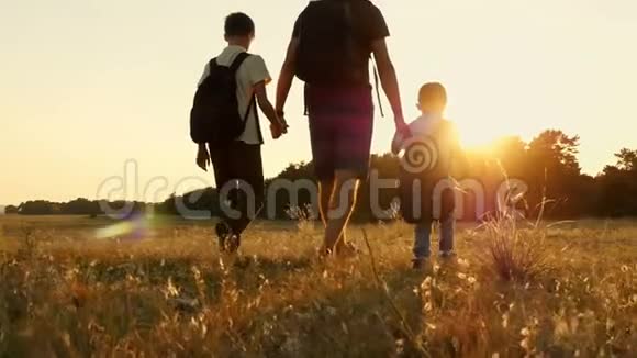 大自然中一个快乐的旅游家庭爸爸和他的两个儿子在日落时背着背包旅游的概念视频的预览图