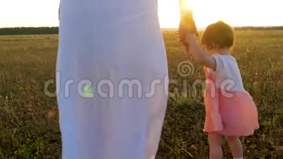 日落时孩子正和妈妈手在公园里散步视频的预览图