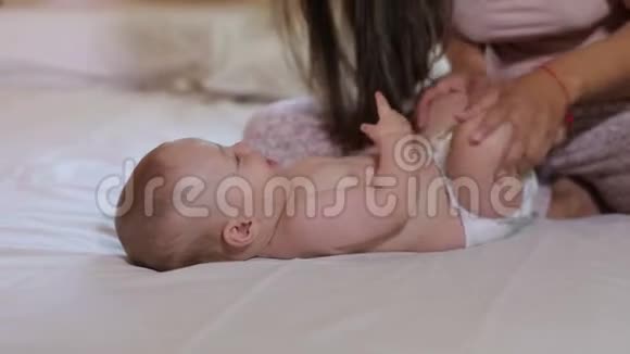 妈妈和刚出生的婴儿在床上玩耍妈妈轻轻地吻着儿子的脚视频的预览图
