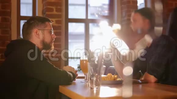 两个人坐在餐厅的桌子旁吃着薯片喝着啤酒视频的预览图
