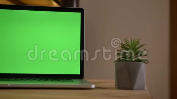 室内办公室小工厂旁桌子上的笔记本电脑的绿色彩色屏幕特写镜头视频的预览图