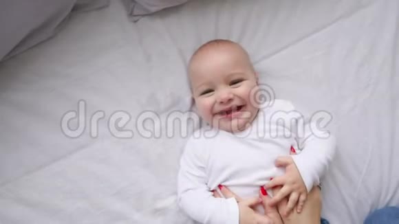 一个新生婴儿躺在床上看着相机和周围的白色床单从上面看婴儿知道视频的预览图