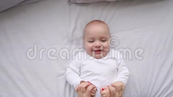 一个新生婴儿躺在床上看着相机和周围的白色床单从上面看婴儿知道视频的预览图