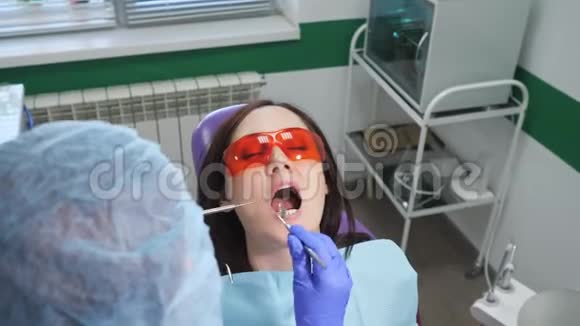 戴防护眼镜的年轻女孩在牙科诊所的牙科椅上进行预防性检查牙齿护理概念视频的预览图