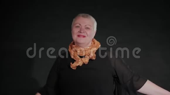 五十岁的女人在黑色背景上拧着呼啦圈视频的预览图