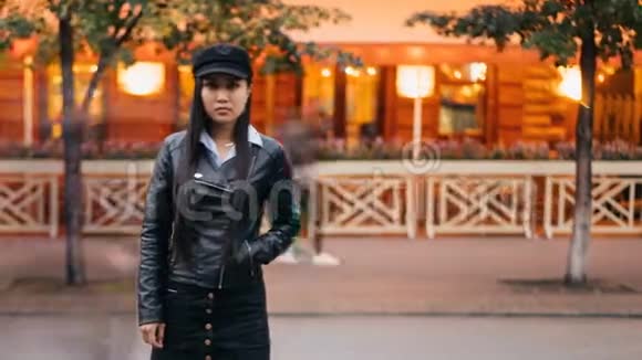 一张疲惫的亚洲女孩站在步行街上手插在口袋里然后看着摄像机的照片视频的预览图