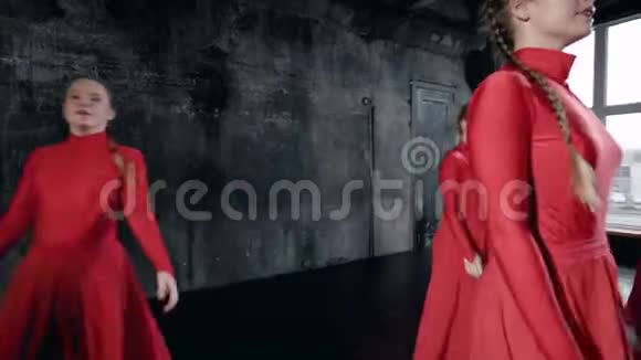 精力充沛的年轻女孩穿着红色舞蹈服装在黑墙的工作室里表演集体舞视频的预览图