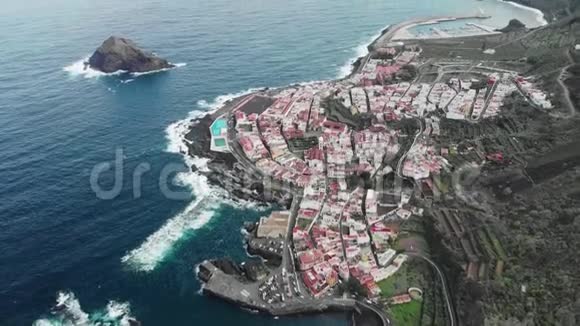 空中射击长海岸线强浪蓝色的海洋和火山海岸有白色房子和红色屋顶的小镇视频的预览图