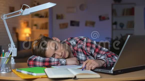 极度疲劳的学生睡在一堆书上的桌子旁超负荷的学生视频的预览图