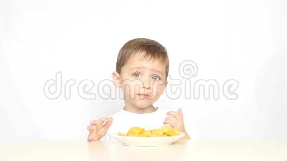 一个喜欢吃薯片的孩子他的拇指放在白色背景的桌子旁视频的预览图