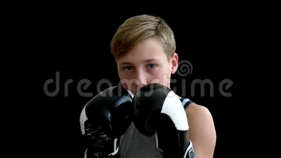 一个十几岁的拳击手站在黑暗的背景上这个男孩有一头金发和一双黑眼睛上面是一件灰色的T恤衫这个男孩是视频的预览图