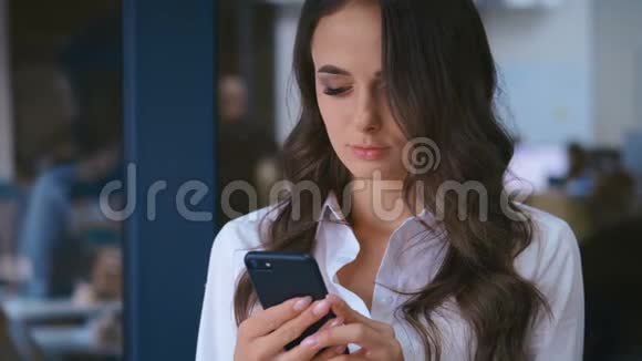 一位年轻漂亮的商务女性后台办公室里有智能手机发短信视频的预览图