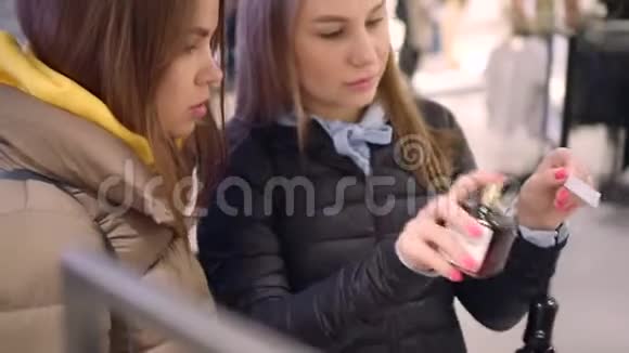 漂亮的女人尝试口味给她的朋友一家商店的香水部视频的预览图