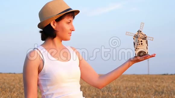 玩具风车在一个年轻女孩的手中背景是麦田收割的概念视频的预览图