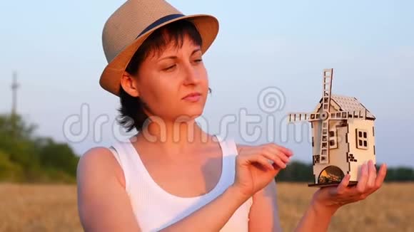 一个女孩站在麦田里手里拿着一个玩具风车女孩慢慢地转动风车的概念视频的预览图