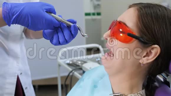 当医生站在病人旁边时年轻的女人害怕拔掉一颗牙齿坐在牙科椅上抱着病人视频的预览图