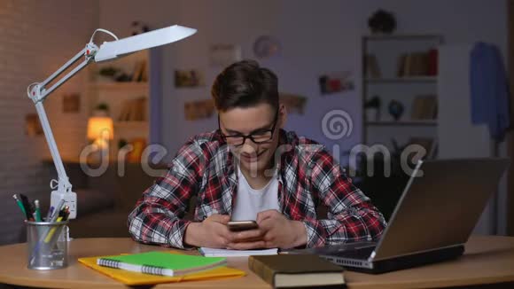 戴眼镜的青少年学生坐在桌子旁和朋友在智能手机上聊天视频的预览图
