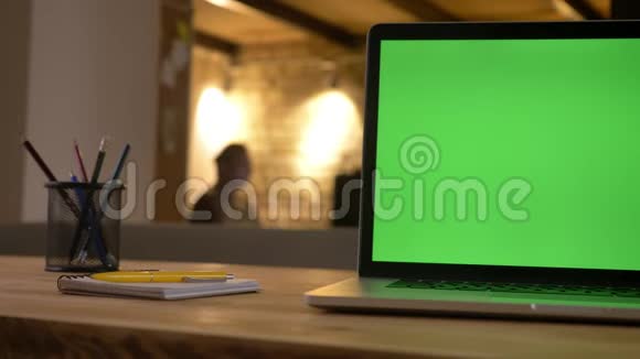 笔记本电脑绿色屏幕特写镜头放在杯子旁边的书桌上办公室里放着铅笔视频的预览图