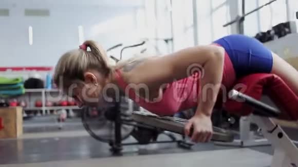 年轻的女运动员在背部肌肉上工作带重量的超伸视频的预览图