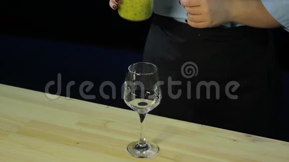 一个女人把碎奇异果和芒果用冰沙倒入玻璃杯视频的预览图