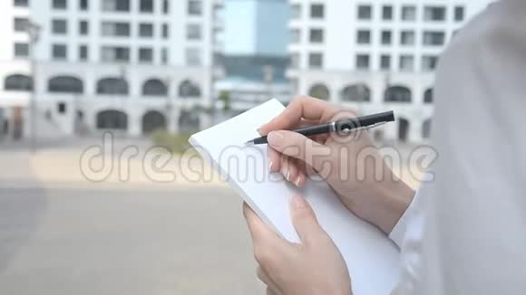 女性手持记事本记录城市背景视频的预览图