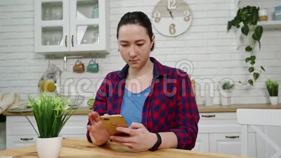 手里拿着智能手机的女人正在写信息她坐在厨房里视频的预览图