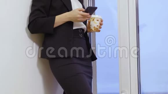 漂亮的金发女人拿着咖啡杯在办公室里用手机视频的预览图