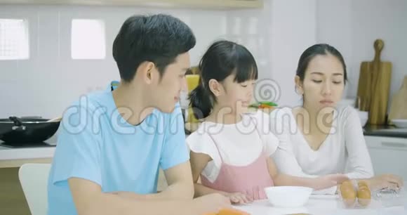 微笑的亚洲父亲母亲和女儿喜欢一起在厨房准备健康的晚餐视频的预览图