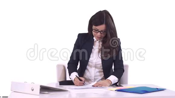 商业女性的肖像布鲁内特戴着眼镜坐在办公室里签着文件微笑着把它们交给了视频的预览图