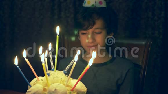 男孩许了个愿在黑暗的房间里看着蛋糕上的蜡烛4k慢动作视频的预览图